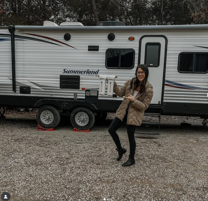 Woman standing in front of a Summerland travel trailer