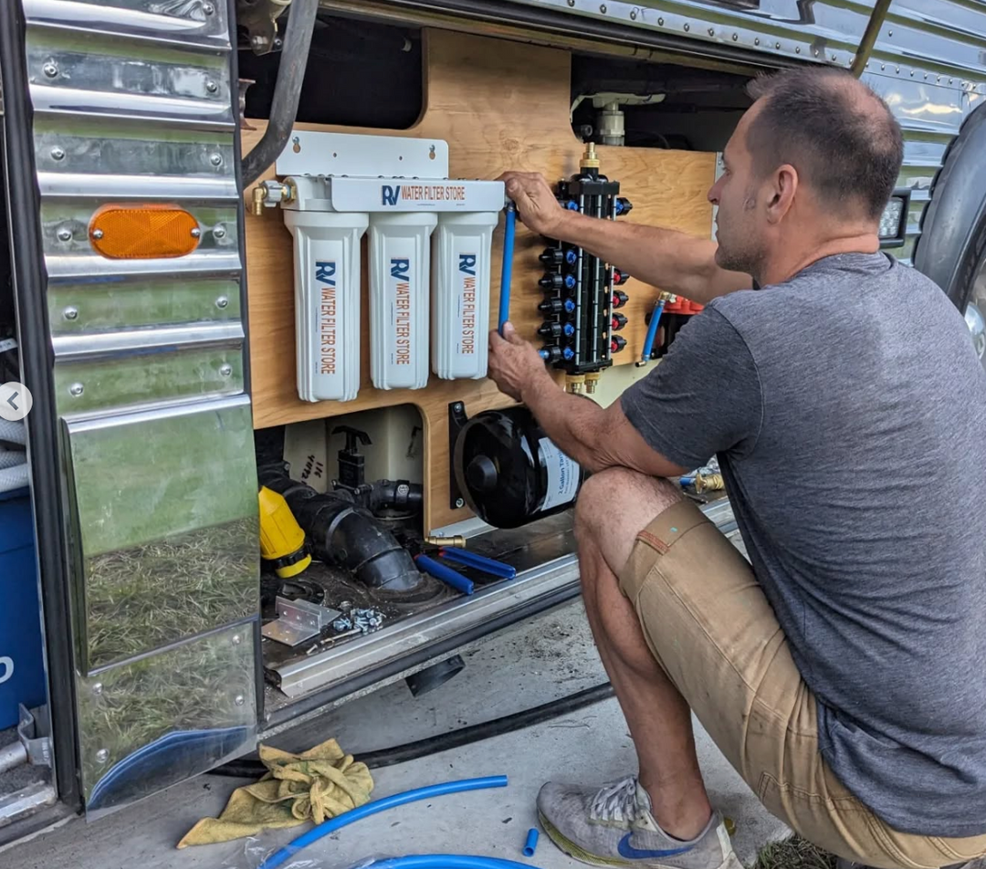 Person working on RV water filtration system inside a vehicle