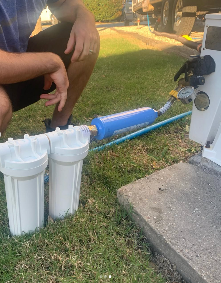 Person using a water filter system on grass with a vehicle in the background